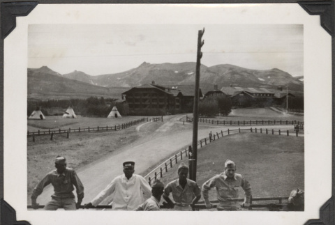 Four men leaning on railing with Tipis in background (ddr-densho-466-188)