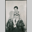 Child sitting on stool covered in a blanket (ddr-densho-523-240)