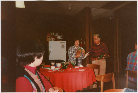 Tomoye and Henri Takahashi standing by table with gifts (ddr-densho-426-1292)