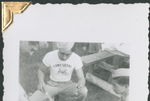 Man in Camp Grant t-shirt cooking hamburgers (ddr-densho-434-214)