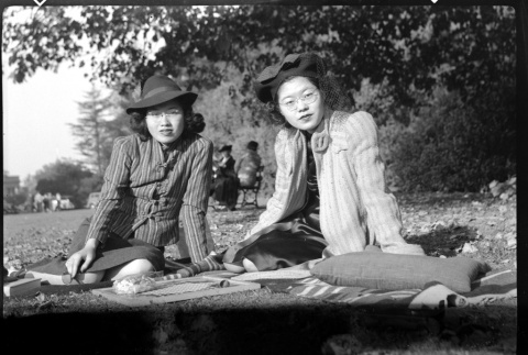 Martha (Nozawa) Tsuchida Suzuki and Tomoye (Nozawa) Takahashi seated on a blanket outside (ddr-densho-426-1737)