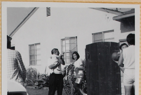Man holding baby, two men playing basketball (ddr-densho-522-88)
