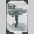Soldier standing on a rocky outcrop (ddr-densho-201-744)