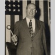 Judge posing in front of a flag, holding a gavel (ddr-njpa-2-796)