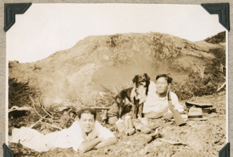 Two men with dog resting on hillside (ddr-densho-383-63)