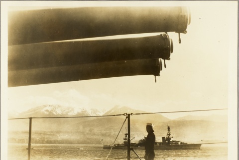 Sailor standing on a ship's deck next to cannons (ddr-njpa-13-341)
