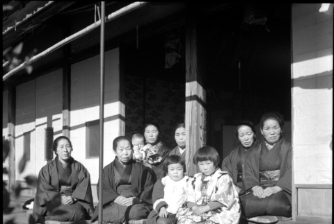 Group of women and children seated in doorway of house (ddr-densho-426-313)
