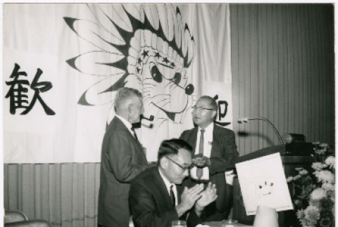 Three men at speakers table with banner in background (ddr-ajah-2-15)