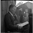 Man seated on bench reading a paper (ddr-densho-426-1746)