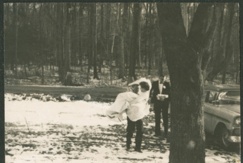 Black and white photos of groom carrying bride in snowy woods (ddr-densho-523-385)