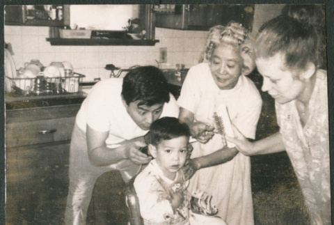 Boy getting haircut, with family around (ddr-densho-523-422)