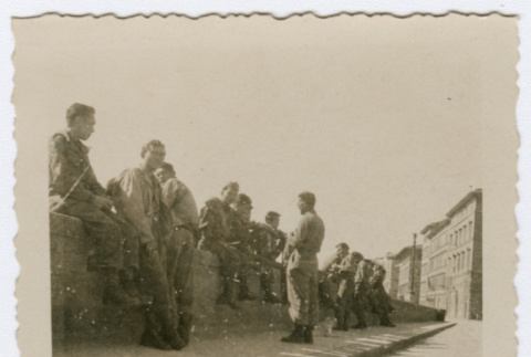 Soldiers sitting on wall next to city sidewalk (ddr-densho-368-82)