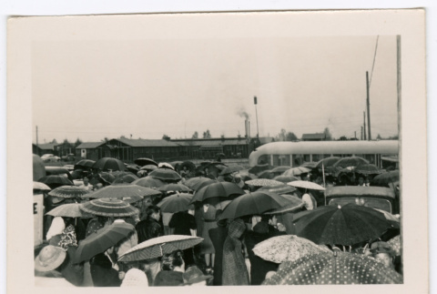 People loading onto a bus holding umbrellas (ddr-densho-475-392)