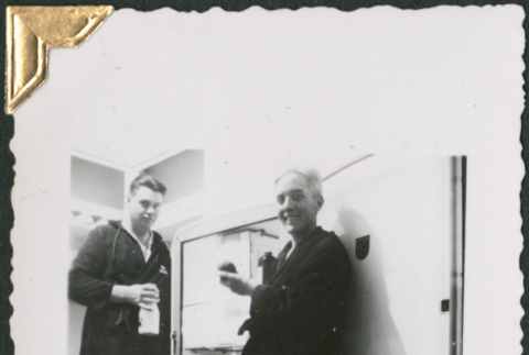 Two men standing by refrigerator (ddr-densho-434-152)