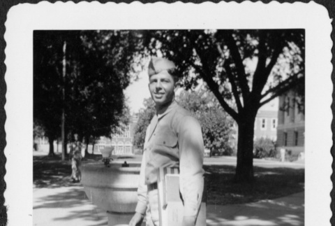 Man with stack of books standing by water fountain (ddr-densho-434-453)