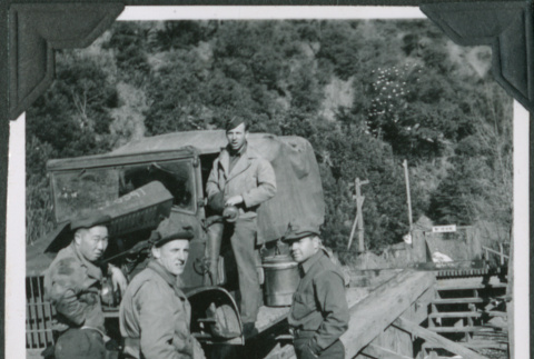 Four men standing by truck on bridge (ddr-ajah-2-375)