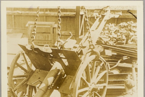 Worker standing next to an anti-aircraft gun in a scrapyard (ddr-njpa-13-263)