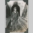 Man standing by entrance to tunnel with rifle and lantern (ddr-ajah-2-322)