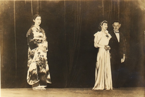 Woman in a kimono and a man and woman in Western clothing standing on a stage (ddr-njpa-4-27)