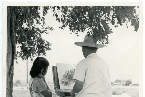 Photograph of an artist painting at an easel while a young girl watches (ddr-csujad-47-72)