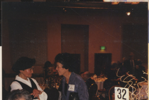 Women talking by banquet tables (ddr-densho-466-557)
