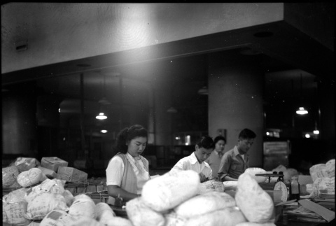 Three people packing items for shipping (ddr-densho-426-946)