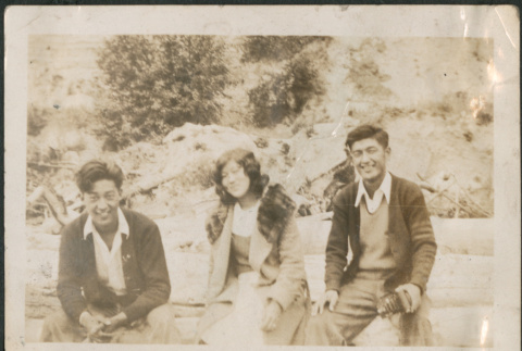 Two men and a woman sitting on logs (ddr-densho-316-304)