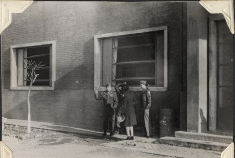 Three men and a woman standing outside building (ddr-densho-466-875)
