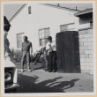 Man standing next to gate in driveway (ddr-densho-522-100)