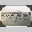 Men resting outside row of tents with trucks in background (ddr-ajah-2-222)