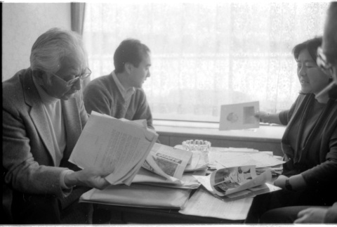 Loni Ding, Barry Saiki, Harry Fukuhara and one other looking through clippings (ddr-densho-1007-1170)