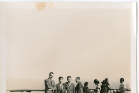 Group standing on deck of ship by railing (ddr-densho-426-2147)