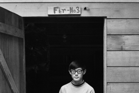 Alan Tani standing in a cabin doorway (ddr-densho-336-159)
