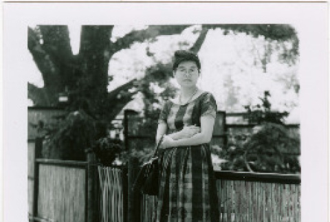 Tomoye (Nozawa) Takahashi standing by fence (ddr-densho-426-2206)