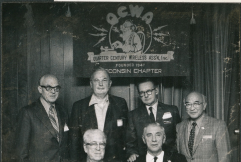 Six men in front of sign for Wisconsin Chapter of Wireless Association (ddr-densho-523-617)