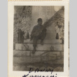 Man sitting on base of monument holding a branch (ddr-densho-466-355)