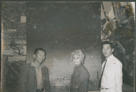 Agnes Sakura and two men standing by large photo(?) (ddr-densho-523-444)