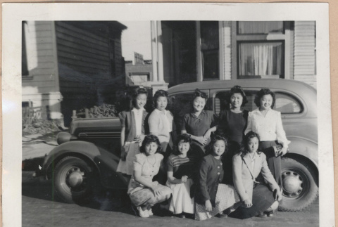 Group of women in front of a car (ddr-manz-10-2)