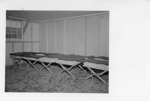 Unmade cots lined up in a barracks (ddr-fom-1-876)