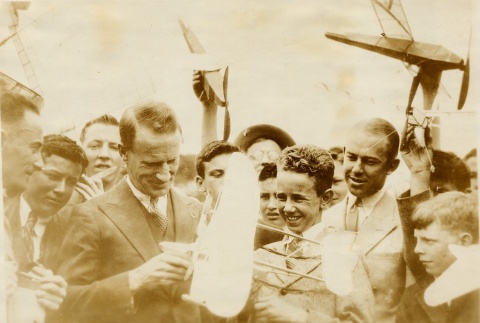 Charles Kingsford Smith holding a model airplane in a crowd of admirers (ddr-njpa-1-727)
