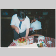 Dave Sato cutting cake (ddr-densho-426-1211)