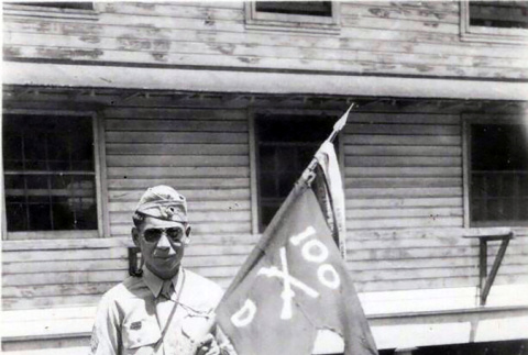Sergeant Hachiro Hashiguchi holding the guidon for his unit, Company D of\nthe 100th Battalion of the 442nd Regimental Combat Team. (ddr-densho-474-235)