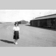 Nisei woman standing near barracks (ddr-densho-111-2)