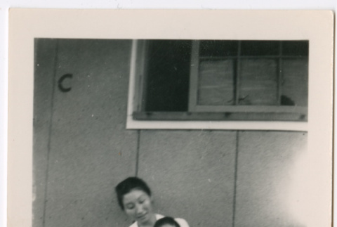 Woman holding toddler girl sitting outside barracks (ddr-densho-329-1277)