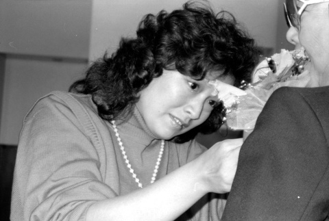 Woman pinning flower onto jacket (ddr-densho-1007-549)