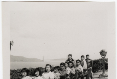 Group sitting on bench at overlook with Oakland Bay Bridge in background (ddr-densho-426-955)