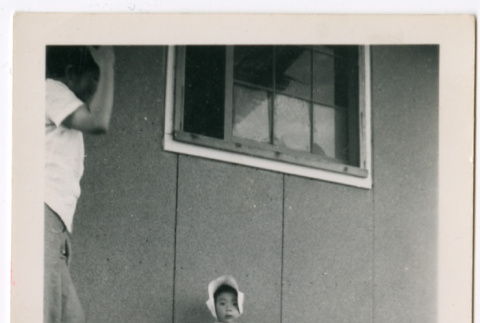 Little girl in bonnet outside barracks (ddr-densho-329-1348)