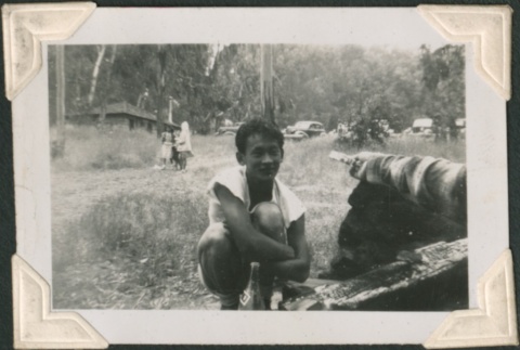 Young man crouching by charred logs (ddr-densho-321-227)