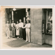 Five men and a woman standing outside business (ddr-densho-426-2130)