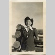 Woman standing in front of a log structure (ddr-manz-6-101)
